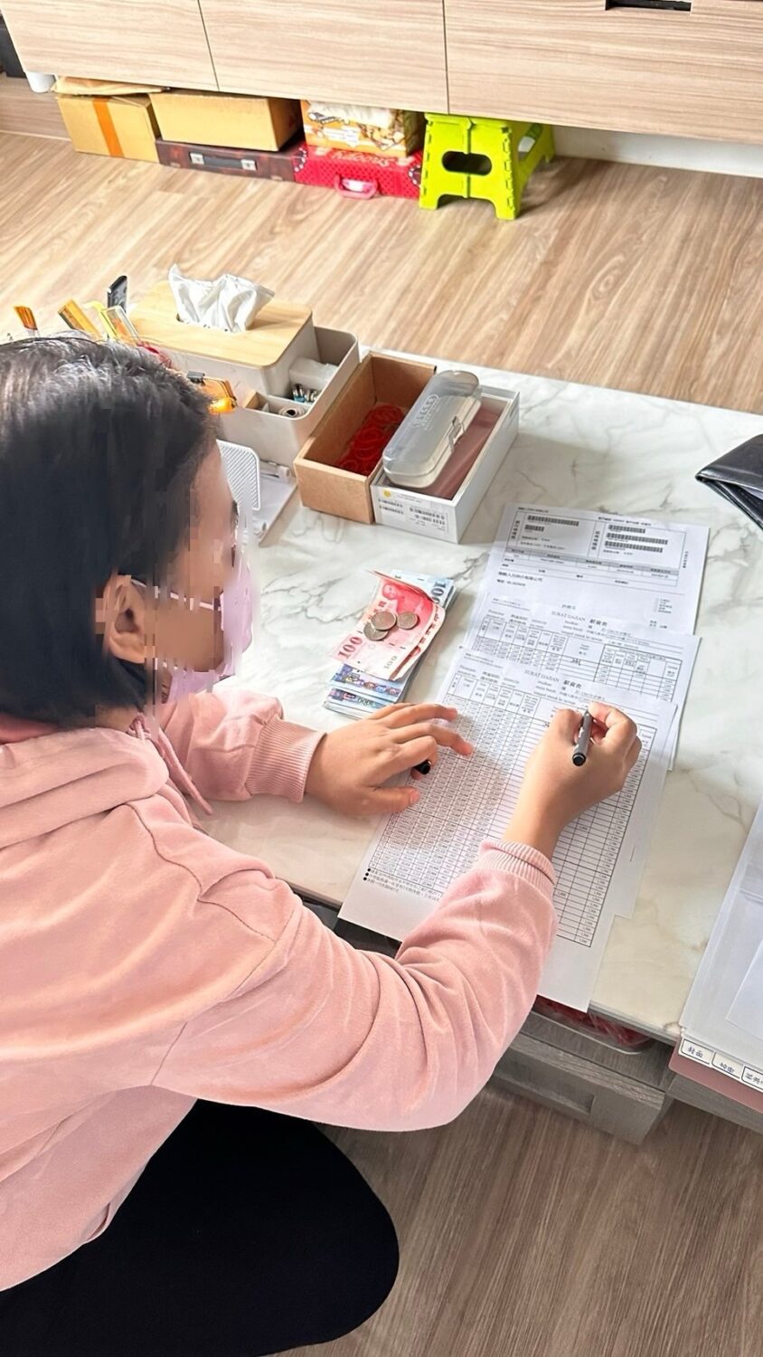 一名在辦公桌上填寫表格的人展示新台幣和口罩。
