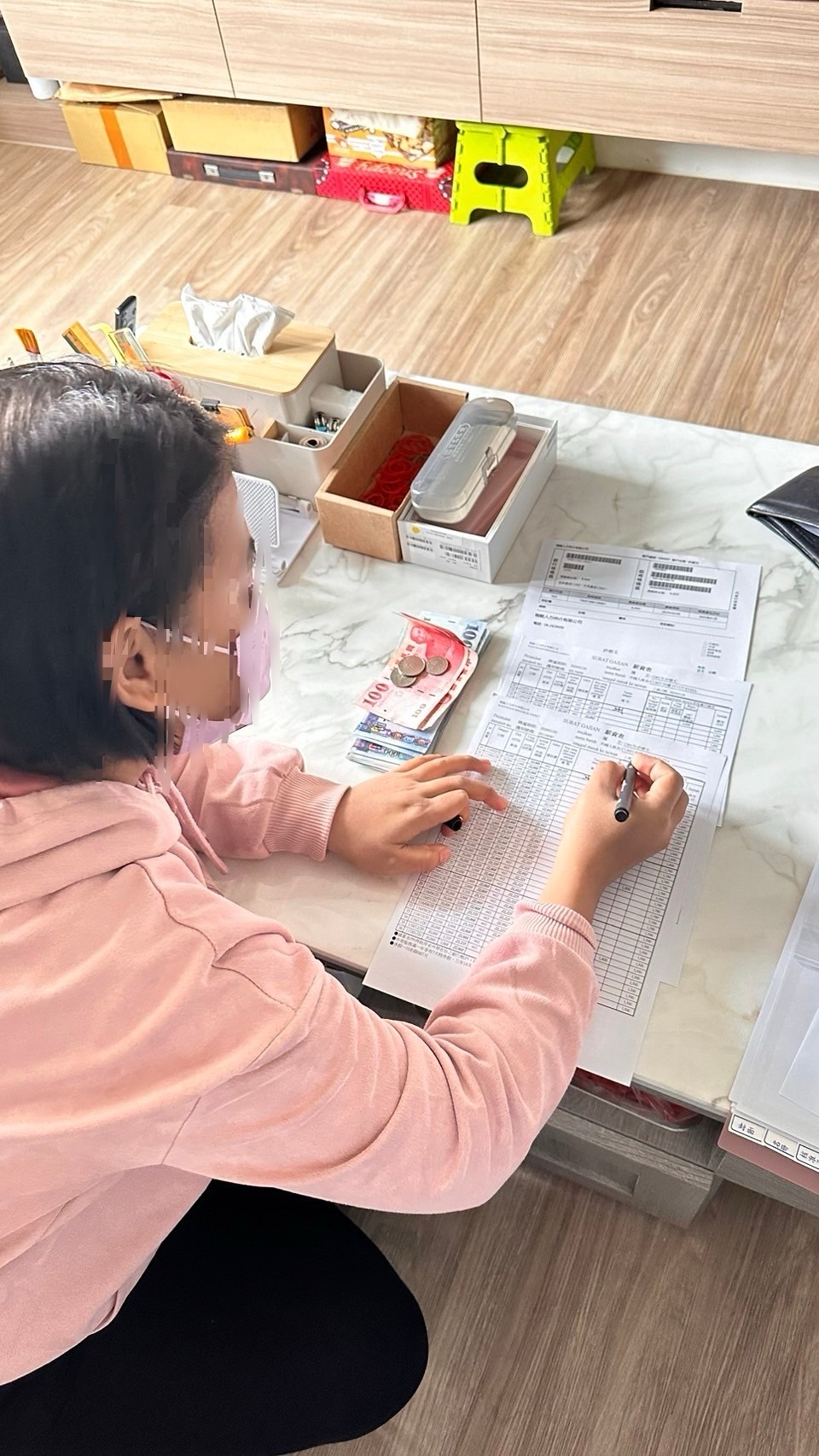 一名在辦公桌上填寫表格的人展示新台幣和口罩。