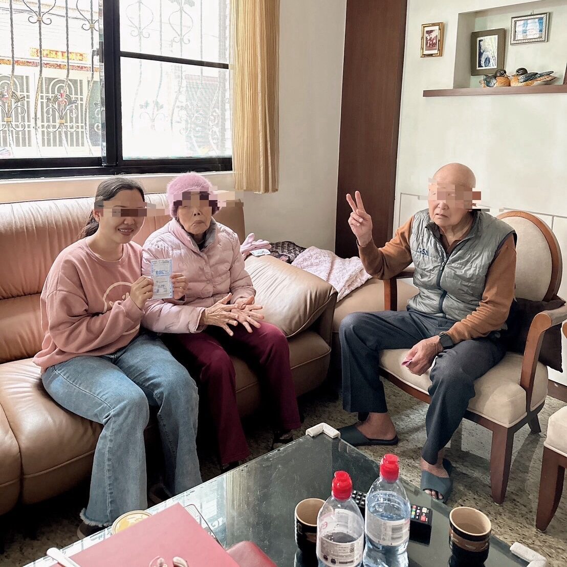 外勞看護工與阿公在沙發，其中兩人微笑。