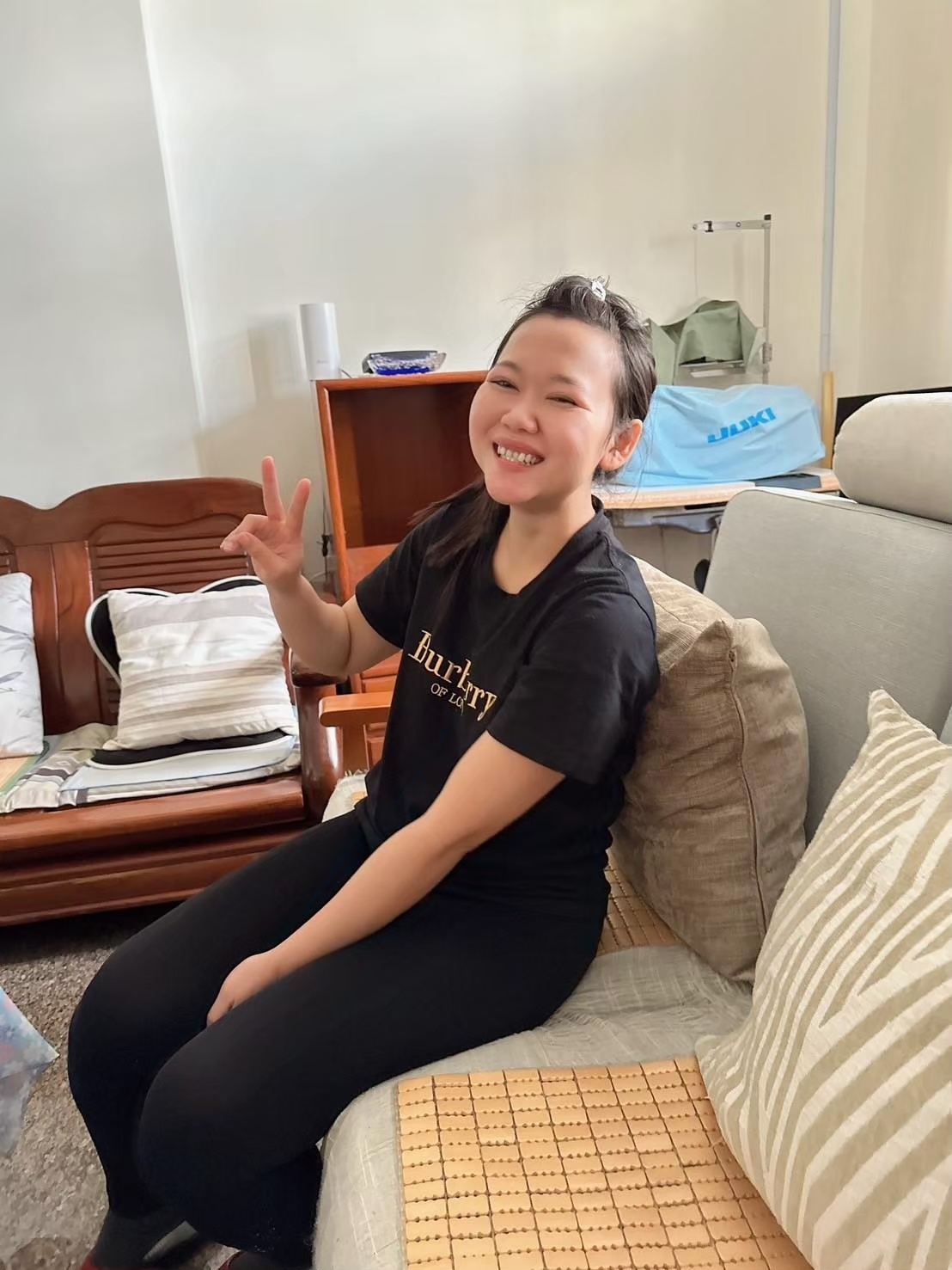 身穿黑色 Burberry 襯衫的快樂年輕女子做出和平手勢。